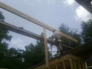 Carpenter setting a ridge beam over a new addition frame — Ice Dam Removal by Roofing Brothers in Bay City