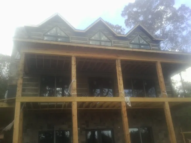 Dormers and porch framing on a large log home under construction — Roof Coating work by our crew in Bay City