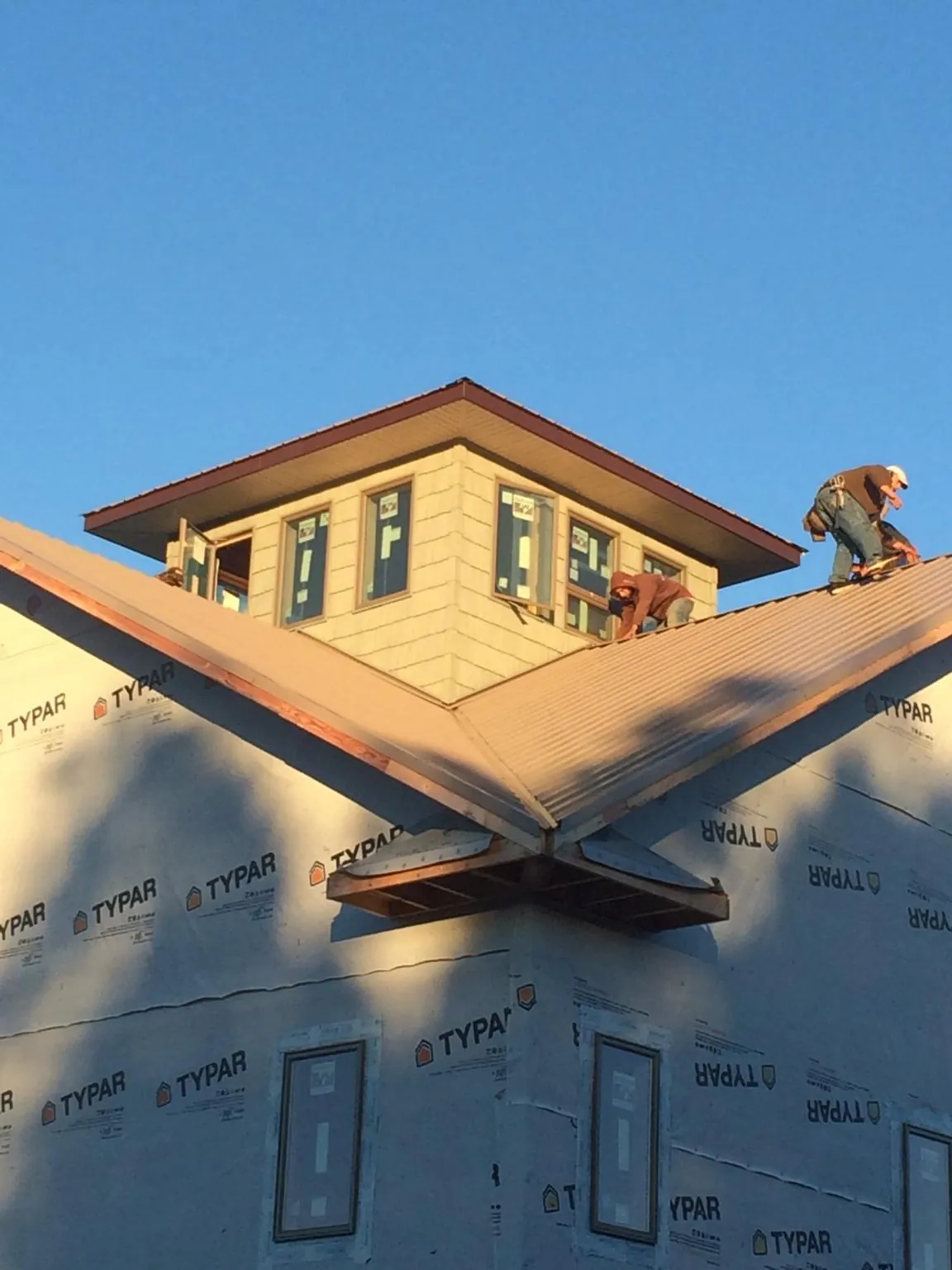 Roofers working around a rooftop cupola on a new metal roof at sunset — Roof Waterproofing in Bay City by Roofing Brothers